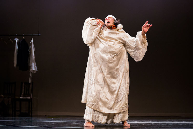 Kawaguchi is in a large white housecoat. He throws his head back and mouth agape.